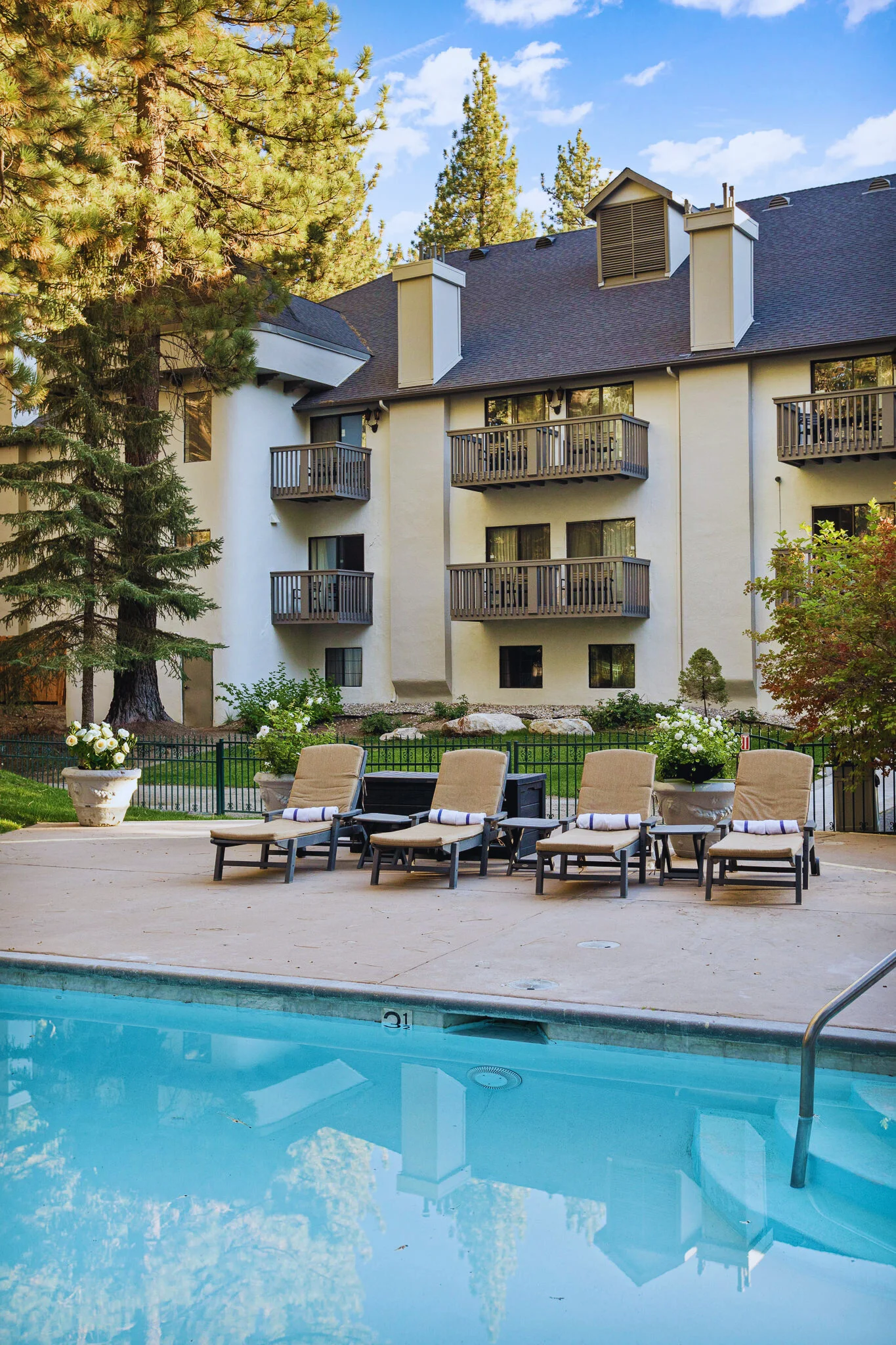 pool lounge chairs with towels, and view of hotel room balconies